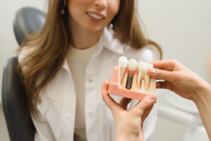 Dental Patient Getting Shown A Dental Implant Model During Her Consultation in Framingham, MA