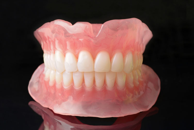 Full upper and lower complete dentures set with realistic gum detail, used for tooth replacement in Framingham, MA